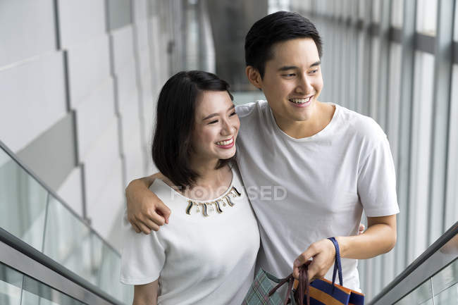 Jovem asiático casal com sacos no shopping — Fotografia de Stock