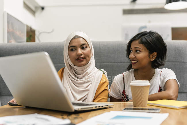 Mulheres de negócios multiculturais jovens que trabalham com laptop no escritório moderno — Fotografia de Stock