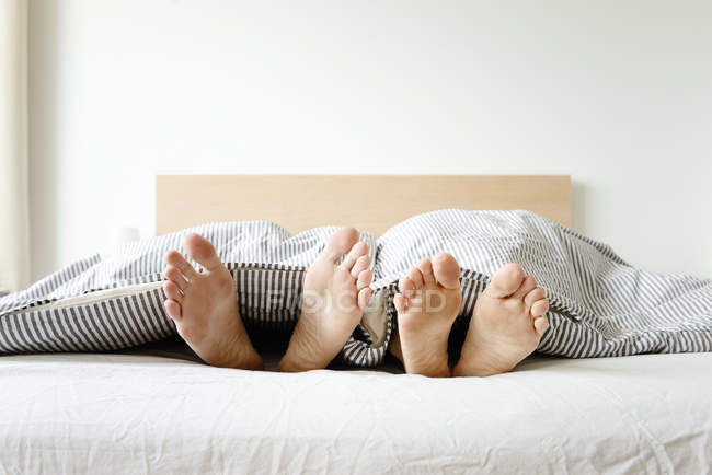 Обрізане зображення пари, що лежить у ліжку, лише ноги — стокове фото