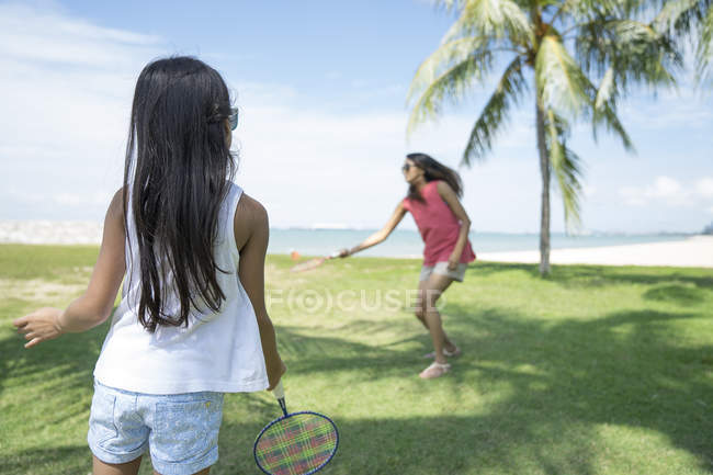 Мать и дочь играют в бадминтон на пляже — стоковое фото