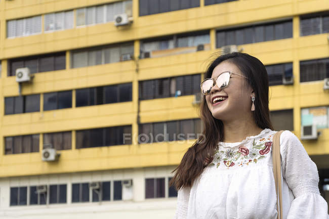Young casual asian girl in sunglasses posing at camera — Stock Photo