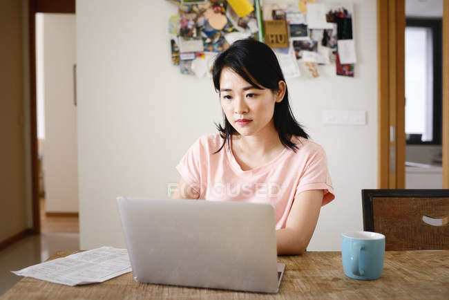 Jovem casual asiático mulher usando laptop em casa — Fotografia de Stock