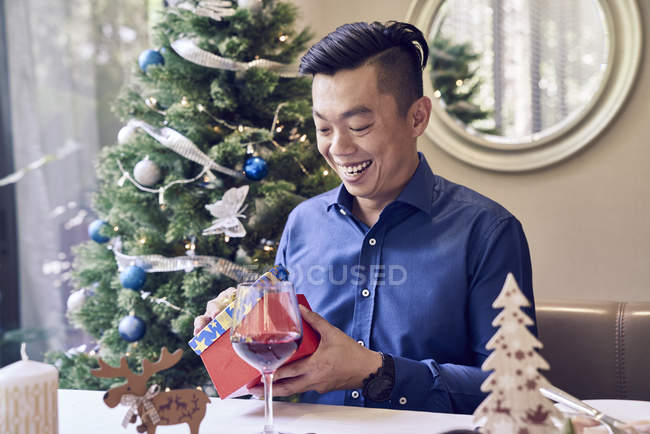 Happy young asian man celebrating christmas and holding gift — Stock Photo