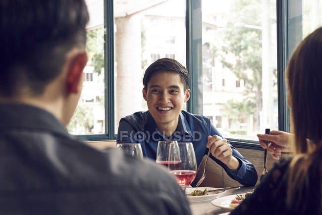 Compañía de jóvenes amigos asiáticos juntos comiendo en la cafetería - foto de stock