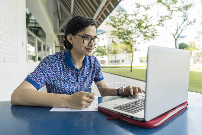 Estudante malaio trabalhando no projeto da escola no laptop — Fotografia de Stock