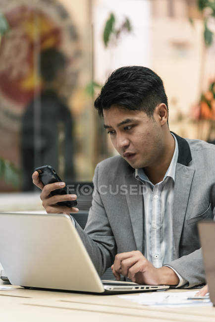 Young asian business man using smartphone in modern office — Stock Photo