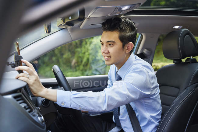 Jovem motorista do sexo masculino verificando direções em seu GPS — Fotografia de Stock