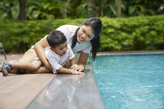 Madre e hijo unidos junto a la piscina - foto de stock