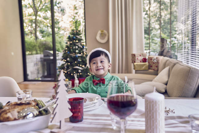 Щасливий молодий азіатський хлопчик святкує Різдво за столом — стокове фото