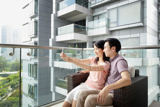 Joven casual asiático pareja tomando selfie en balcón - foto de stock