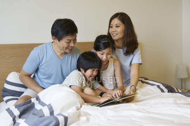 Familie teilt sich ein Buch im Schlafzimmer — Stockfoto