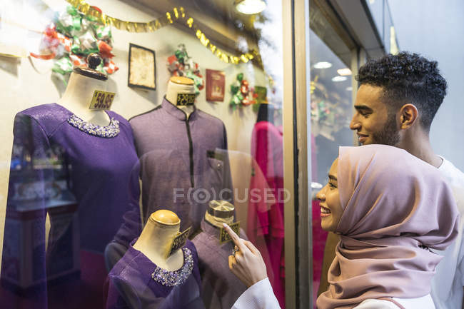 Joven pareja musulmana cerca de la ventana de compras . - foto de stock