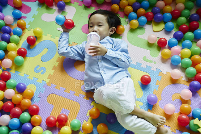 Enfant buvant dans une bouteille de lait dans un stylo de jeu — Photo de stock