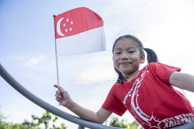 Porträt eines stolzen singaporeanischen Kindes mit Nationalflagge — Stockfoto
