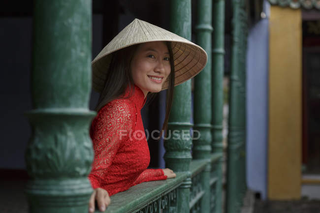 Vietnamesische Frau mit kegelförmigem Hut steht auf einem Balkon in hoi an in ihrem ao dai — Stockfoto