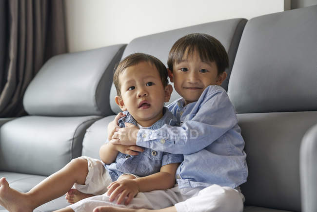 Двое молодых братьев и сестер сидят на диване в гостиной — стоковое фото