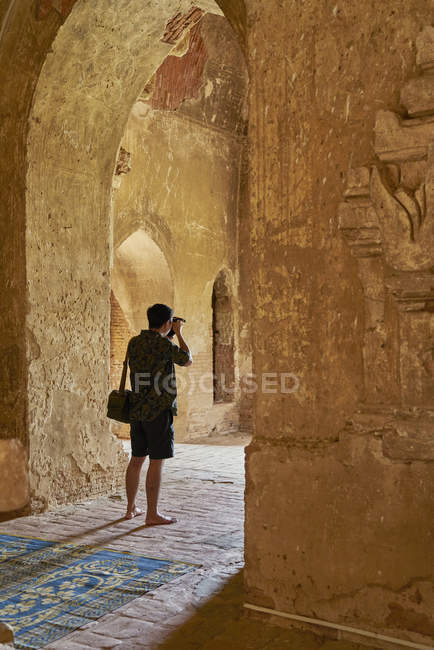 Молодой человек делает фотографию внутри древнего храма, Пагода, Баган, Мьянма — стоковое фото