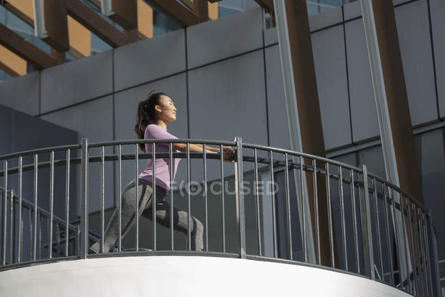 Eine junge asiatische Frau dehnt sich vor ihrem täglichen Lauftraining in Singapores City. — Stockfoto