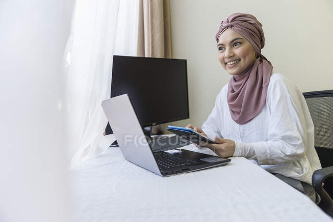 Mujer musulmana de negocios que trabaja en el ordenador portátil desde casa
. - foto de stock