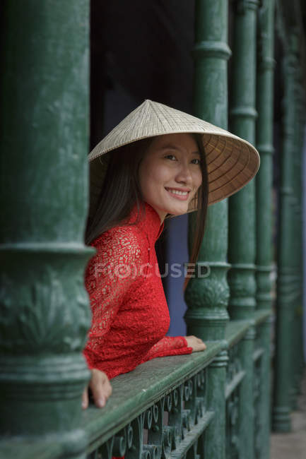 Vietnamese woman wearing conical hat standing on a balcony in Hoi An in her Ao Dai — Stock Photo