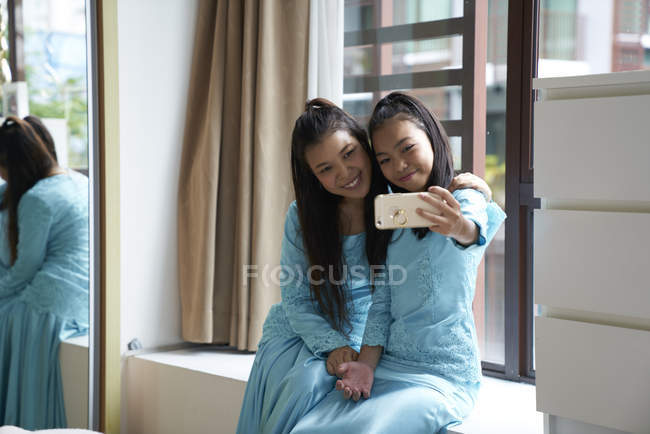 Dos hermana tomando selfie en casa juntos - foto de stock