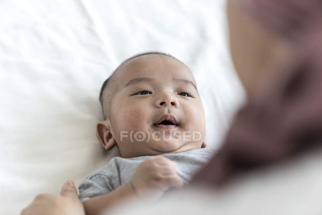 Feliz asiático bebé niño en cama con madre - foto de stock