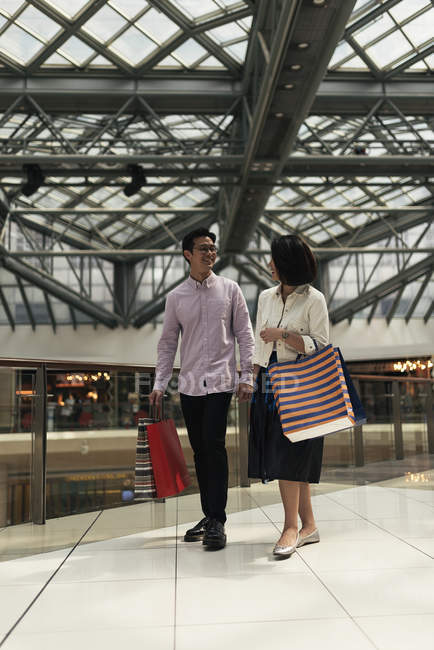 Jovem casual asiático casal com sacos no shopping no shopping — Fotografia de Stock