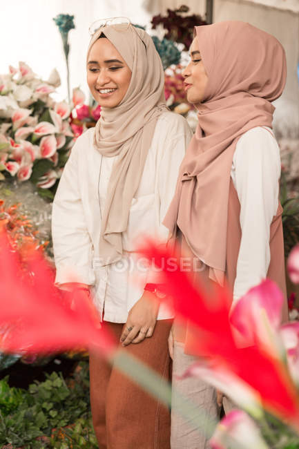 Due giovani ragazze musulmane in negozio di fiori avendo una conversazione divertente — Foto stock