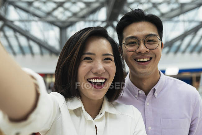 Joven casual asiático pareja tomando selfie en centro comercial - foto de stock