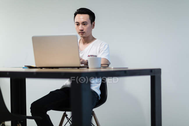 Jovem sorridente usando laptop em um ambiente de inicialização . — Fotografia de Stock