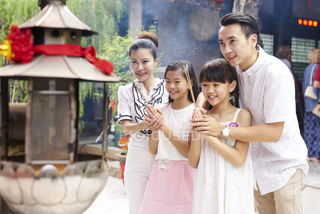 Young happy asian family praying in shrine — Stock Photo