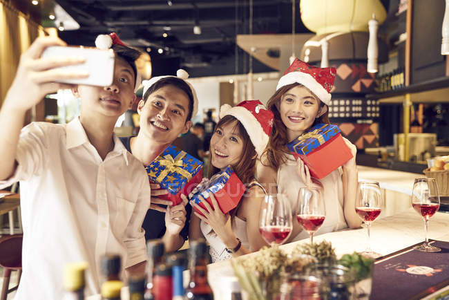 Compagnia di giovani amici asiatici insieme celebrando il Natale e scattando selfie — Foto stock