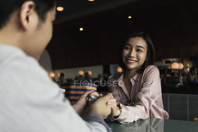 Young asian couple holding hands in bar — Stock Photo