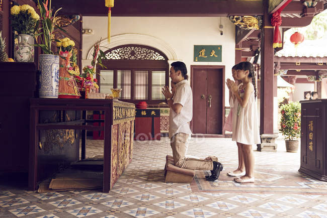 Joven feliz asiático familia orando en shrine - foto de stock
