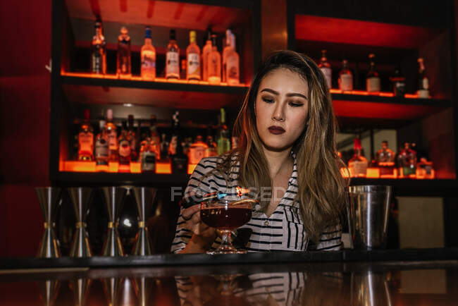 Portrait of young female barman making cocktail in bar — Stock Photo