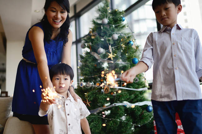 Famiglia asiatica festeggia la festa di Natale con scintille fuochi d'artificio — Foto stock