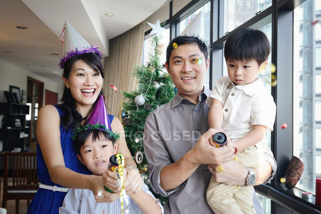 Familia asiática celebrando vacaciones de Navidad con serpentina - foto de stock
