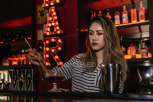 Portrait of young female barman making cocktail in bar — Stock Photo