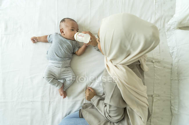 Asiatische muslimische Mutter füttert ihr Baby mit Milch. — Stockfoto