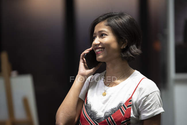 Jovem asiático mulher de negócios falando no smartphone no escritório moderno — Fotografia de Stock