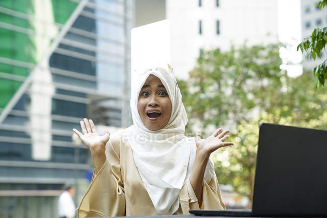 Retrato de uma mulher feliz no parque com seu laptop em Cingapura — Fotografia de Stock