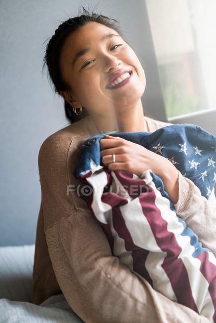 Giovane attraente asiatico donna holding americana bandiera cuscino — Foto stock