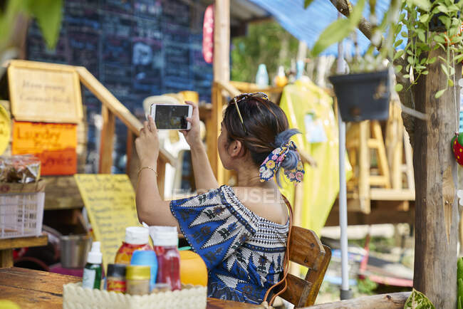 LIBERTAS Mujer joven tomando una foto con su teléfono móvil en una cafetería - foto de stock