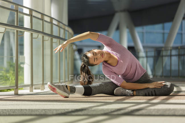Une jeune femme asiatique s'étire avant son entraînement quotidien en ville singapourienne . — Photo de stock