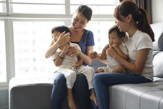 Junge Mütter beim Binden mit ihren Kindern im Wohnzimmer — Stockfoto