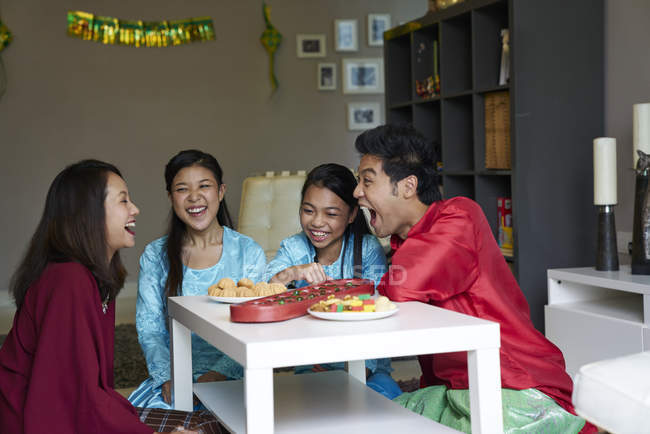 Familia asiática joven celebrando Hari Raya en Singapur y jugando juego tradicional - foto de stock