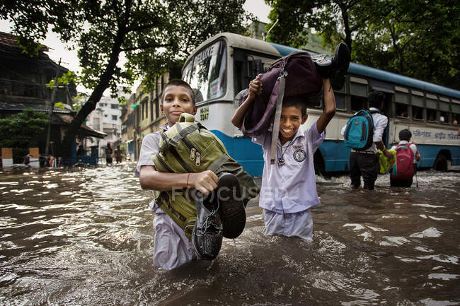 Due bambini stanno tornando a casa attraverso la strada allagata. Il disboscamento dell'acqua è una preoccupazione importante durante la stagione monsonica in India. Questa è una vera sfida per il movimento delle persone e colpisce principalmente i bambini e le donne. — Foto stock
