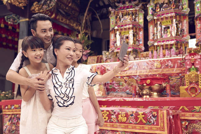 Young happy asian family taking selfie in shrine — Stock Photo