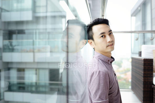 Зрілий азіатський випадковий чоловік стоїть біля вікна — стокове фото