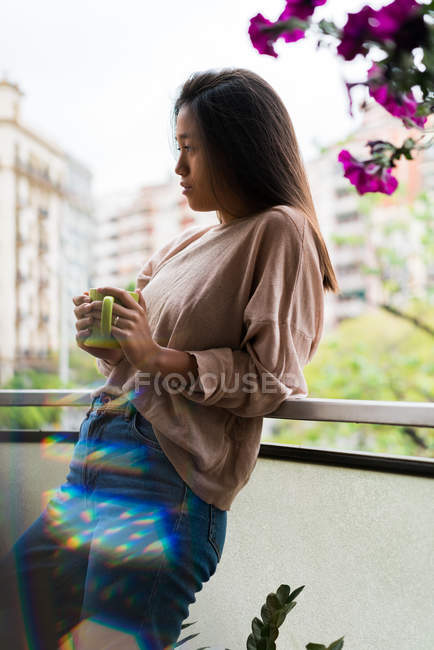 Vista lateral de joven atractiva mujer asiática con taza de café - foto de stock
